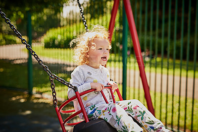 Buy stock photo Shot of an adorable little girl playing on the swing outdoors