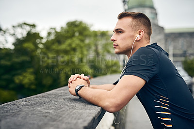 Buy stock photo Shot of a sporty young man taking a break while exercising outdoors