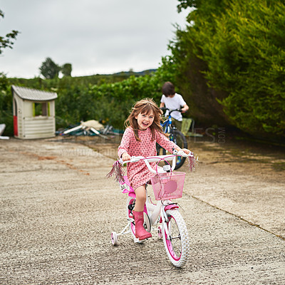 Buy stock photo Portrait of an adorable little girl riding her bike with her brother outdoors