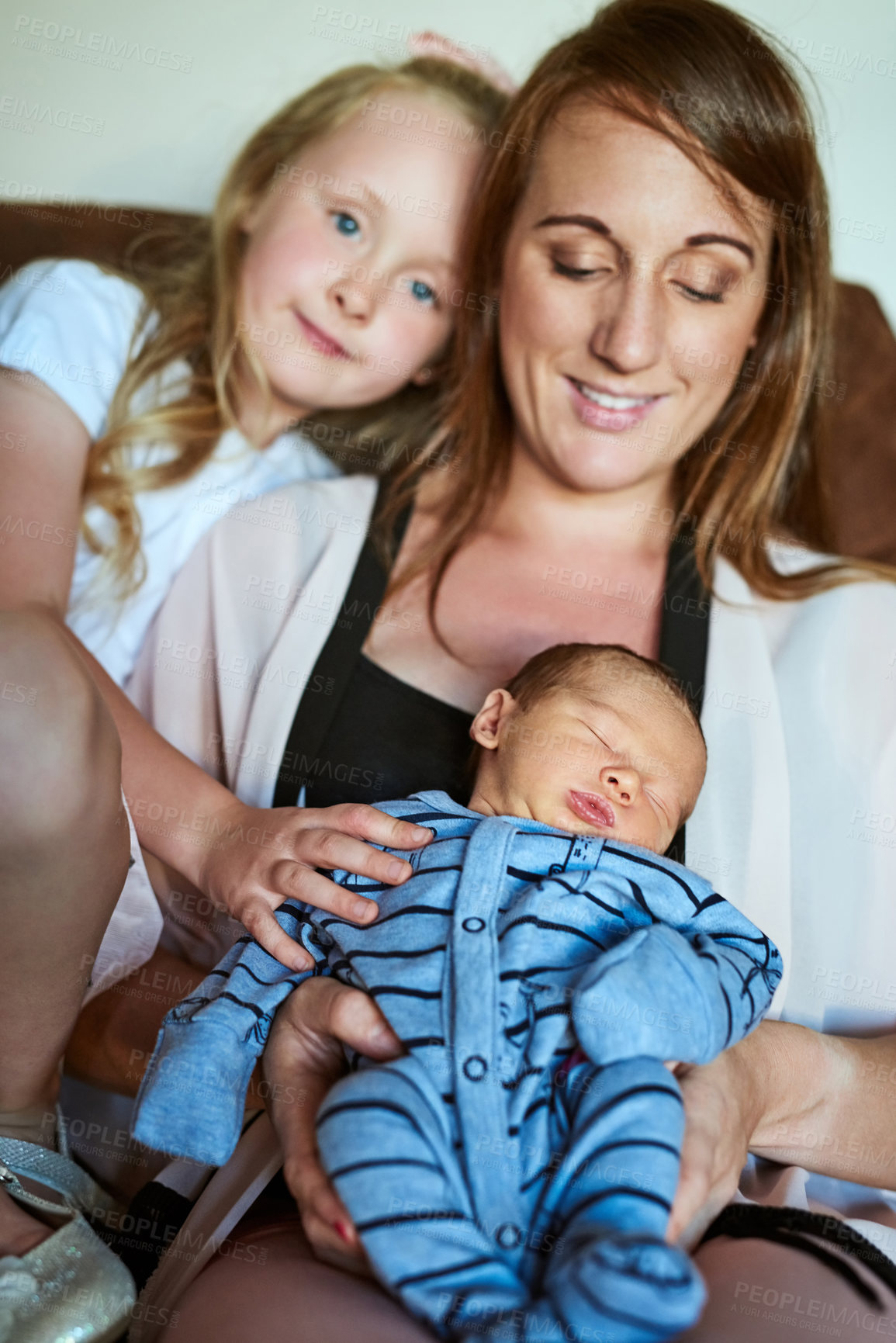 Buy stock photo Shot of a cheerful young family grouped on the couch together in the living room at home