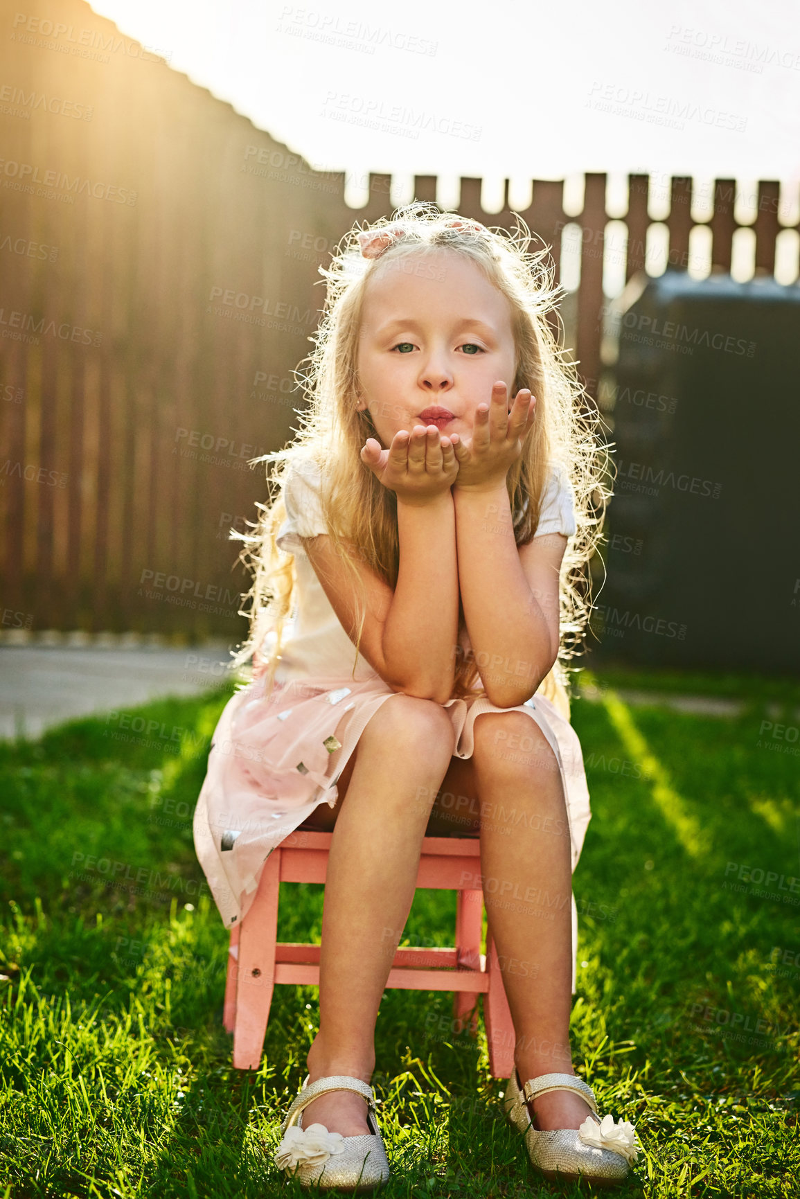 Buy stock photo Child, portrait and blowing kiss outdoor in garden for love, kindness and caring with lens flare. Girl, kid and hand gesture for affection, playing and confidence in backyard lawn in New York home