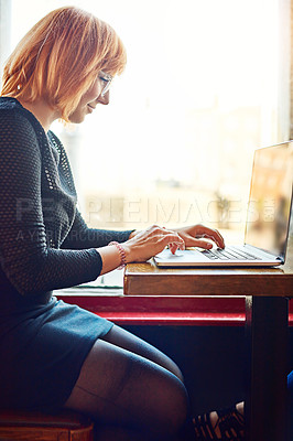 Buy stock photo Cropped shot of a young woman using her laptop in a cafe