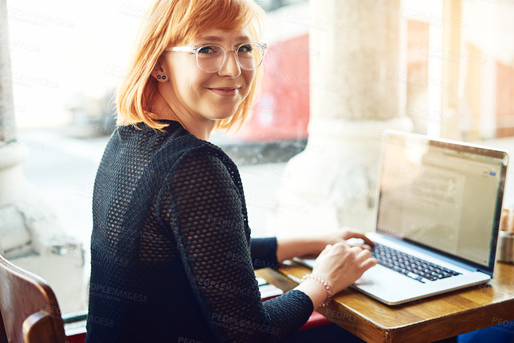 Buy stock photo Cropped shot of a young woman using her laptop in a cafe