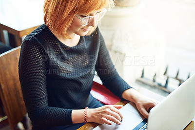 Buy stock photo Cropped shot of a young woman using her laptop in a cafe