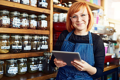 Buy stock photo Shot of a young woman using a digital tablet while working in a coffee shop