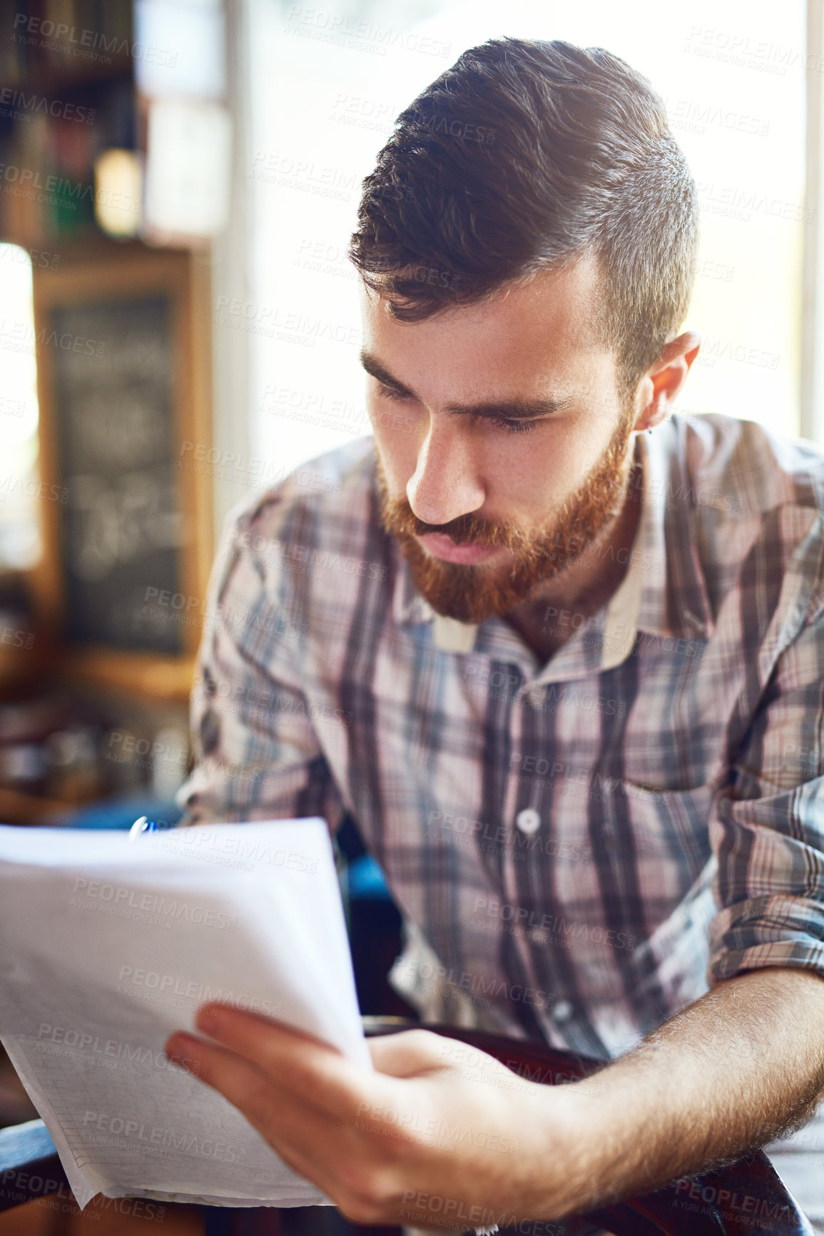 Buy stock photo Man, coffee shop and serious with paperwork for editing as writer or author for review or feedback. Male person, reading and writing on documents in restaurant as professional for media publication