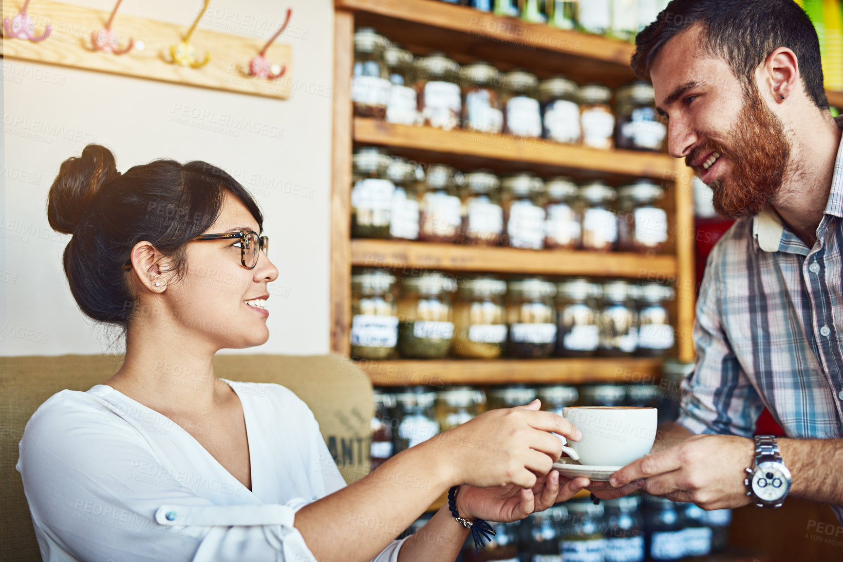 Buy stock photo Shot of a beautiful young woman receiving a cup of coffee from a waiter at a cafe