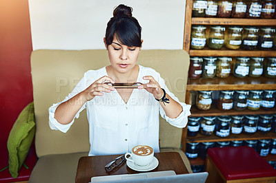 Buy stock photo Shot of a beautiful young woman taking a picture of her coffee with a cellphone in a cafe