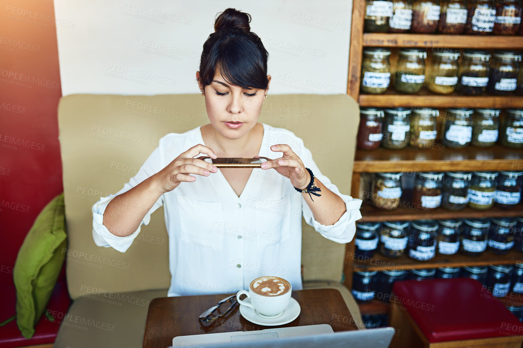 Buy stock photo Shot of a beautiful young woman taking a picture of her coffee with a cellphone in a cafe