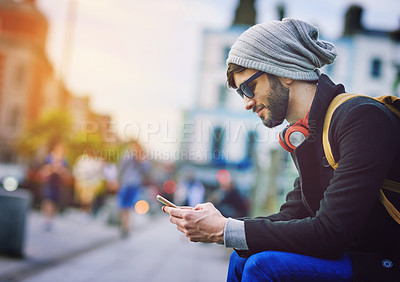 Buy stock photo Smile, man and phone outdoor in city, communication and social media to commute for sightseeing location. Male person, travel and headphones on mobile, station and texting for transport schedule