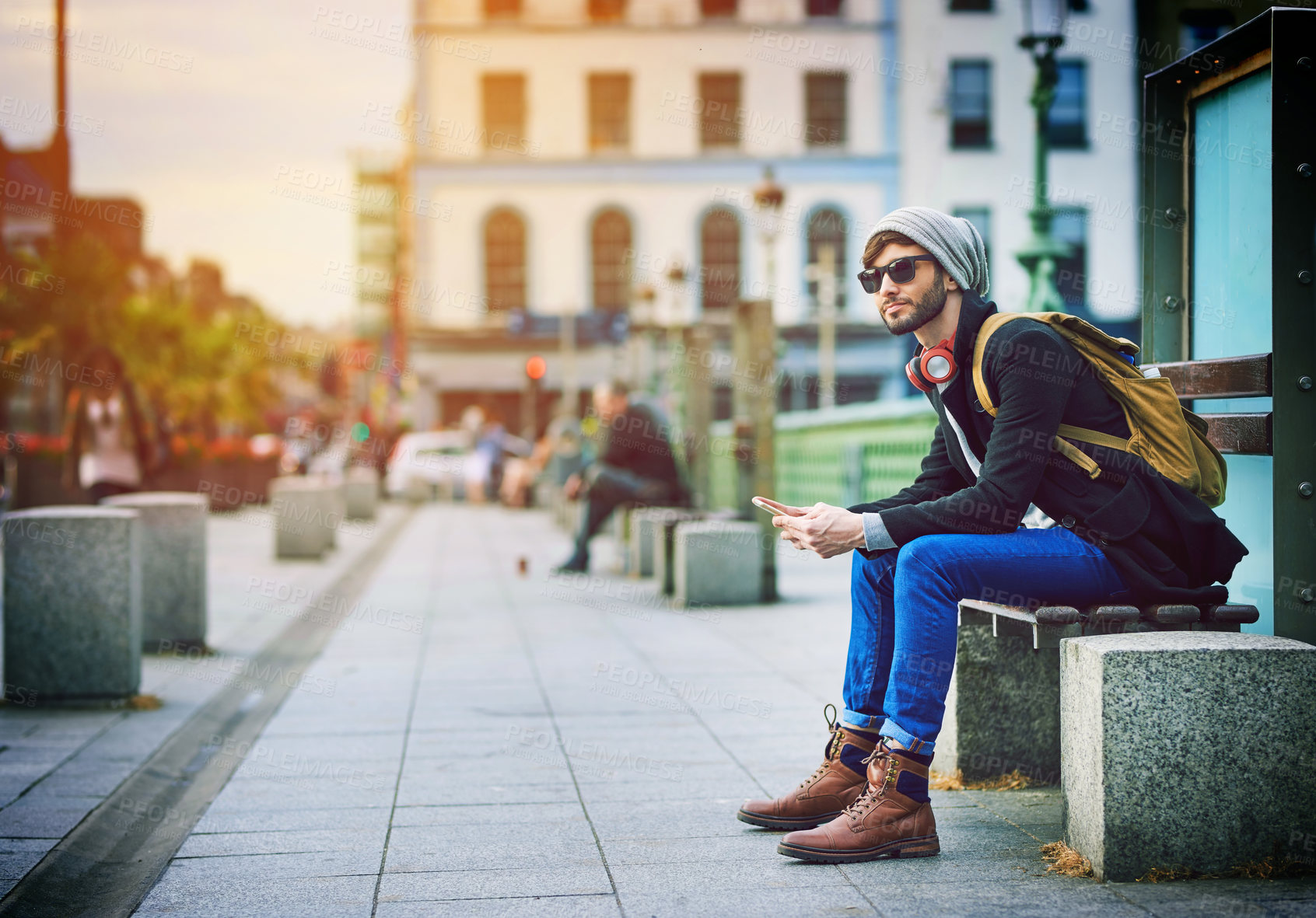 Buy stock photo Thinking, man and phone on bench in city, commute and waiting on bus for ideas of sightseeing or transport. Male person, fashion and headphones on mobile, station and bus stop for journey location
