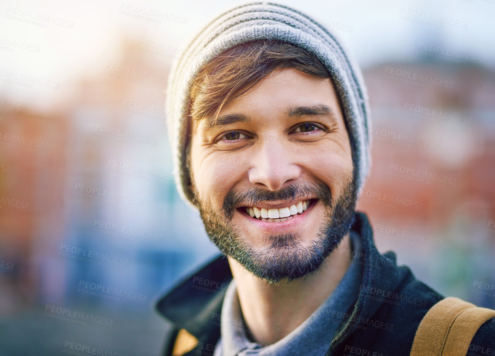 Buy stock photo Man, portrait and happy in city for tourism, sightseeing and travel with blurred background on holiday. Male person, face and commute in urban for adventure, relax and trip with backpack on vacation