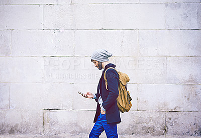 Buy stock photo Shot of a young man using his mobile phone while out in the city