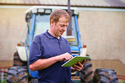 Buy stock photo Shot of a farmer using a digital tablet on his farm