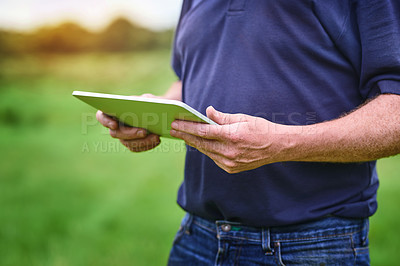 Buy stock photo Shot of an unrecognizable man using a tablet on a farm