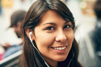 Buy stock photo Cropped portrait of an attractive young woman listening to music while sitting in a bus station