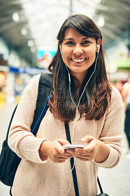 Buy stock photo Cropped portrait of an attractive young woman listening to music while walking through a bus station