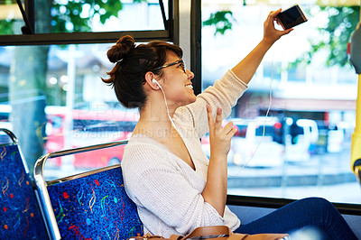 Buy stock photo Cropped shot of an attractive young woman taking selfies with her smartphone while sitting on a bus