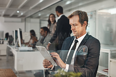 Buy stock photo Cropped shot of a handsome mature businessman working on his tablet in the office