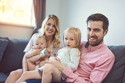 Buy stock photo Portrait of an adorable young family of four relaxing together on the sofa at home