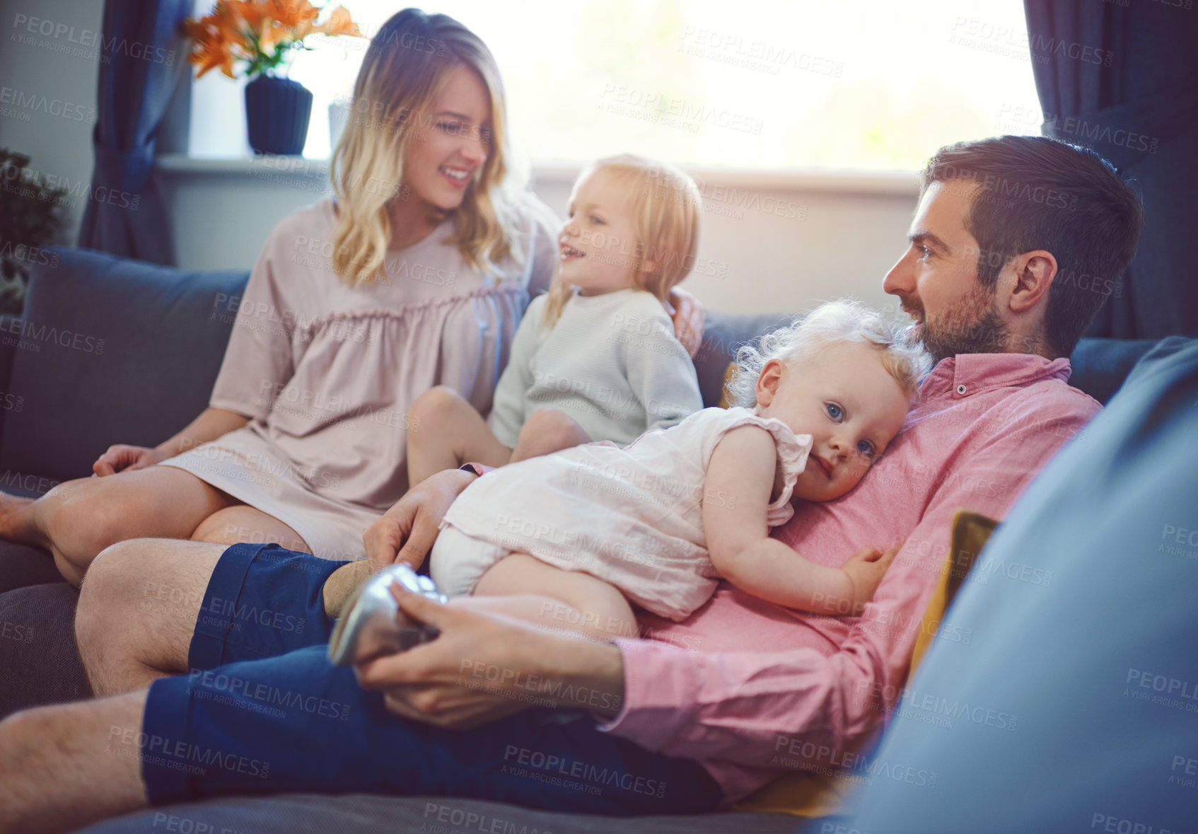 Buy stock photo Shot of an adorable young family of four relaxing together on the sofa at home
