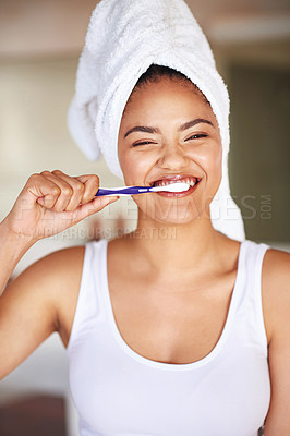Buy stock photo Portrait of a young woman brushing her teeth in the bathroom