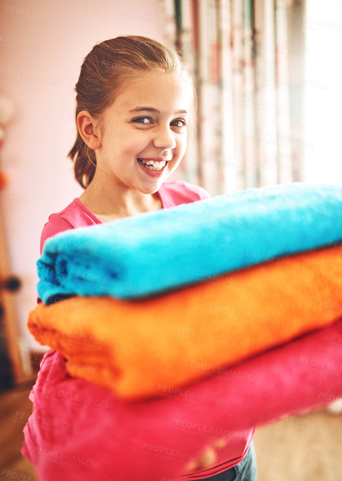 Buy stock photo Kid, girl and home or holding laundry with smile, learning and development or cleaning. Child, job or happy with washing in house or living room, help or support with clothes for family or mother