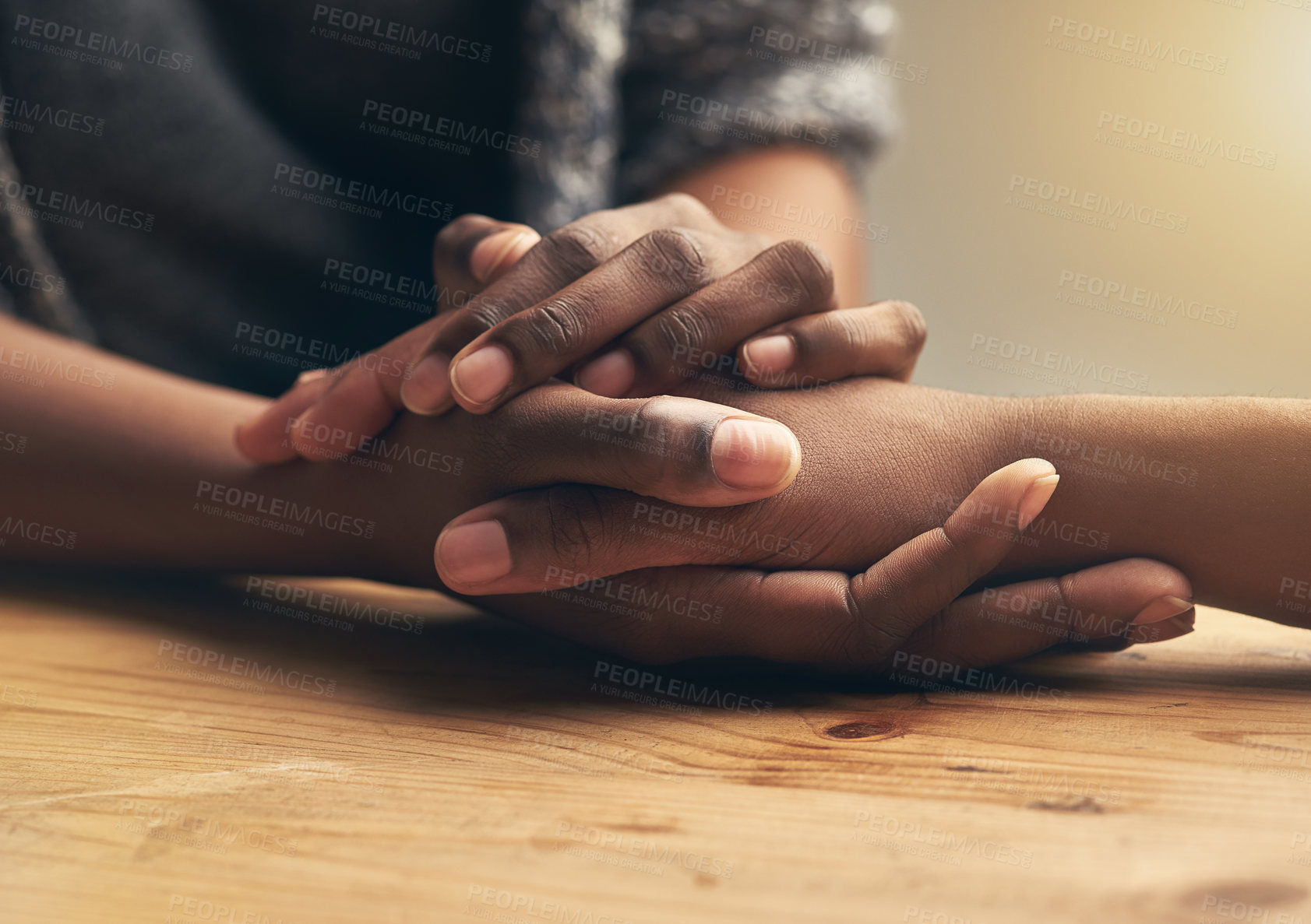 Buy stock photo Comfort, sympathy and people holding hands for unity, compassion and cancer support at wood table. Empathy, care and couple or friends with affection in bonding moment together for grief and loss.