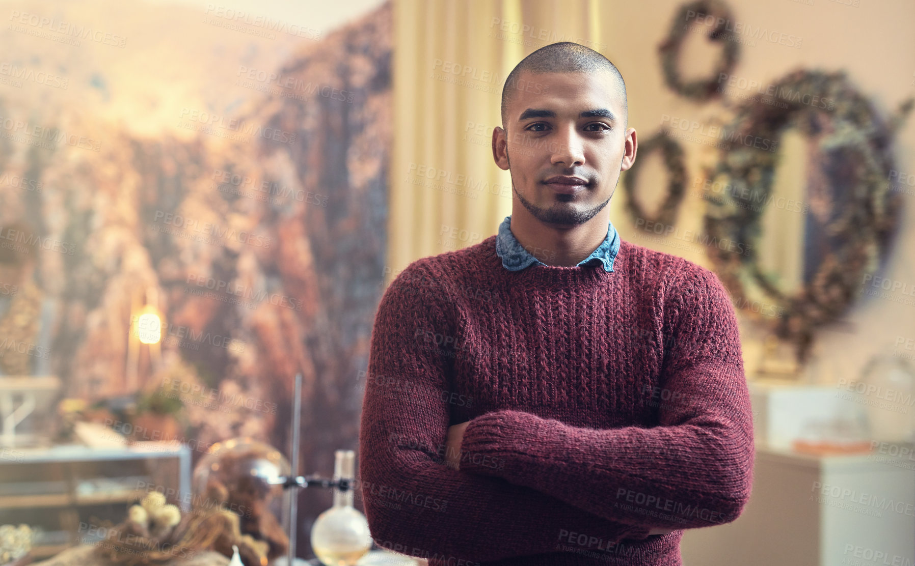 Buy stock photo Cropped portrait of a handsome young male entrepreneur standing with his arms folded in his store