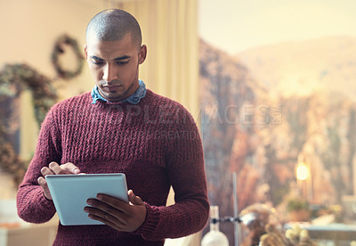 Buy stock photo Cropped shot of a handsome young male entrepreneur using a tablet in his store