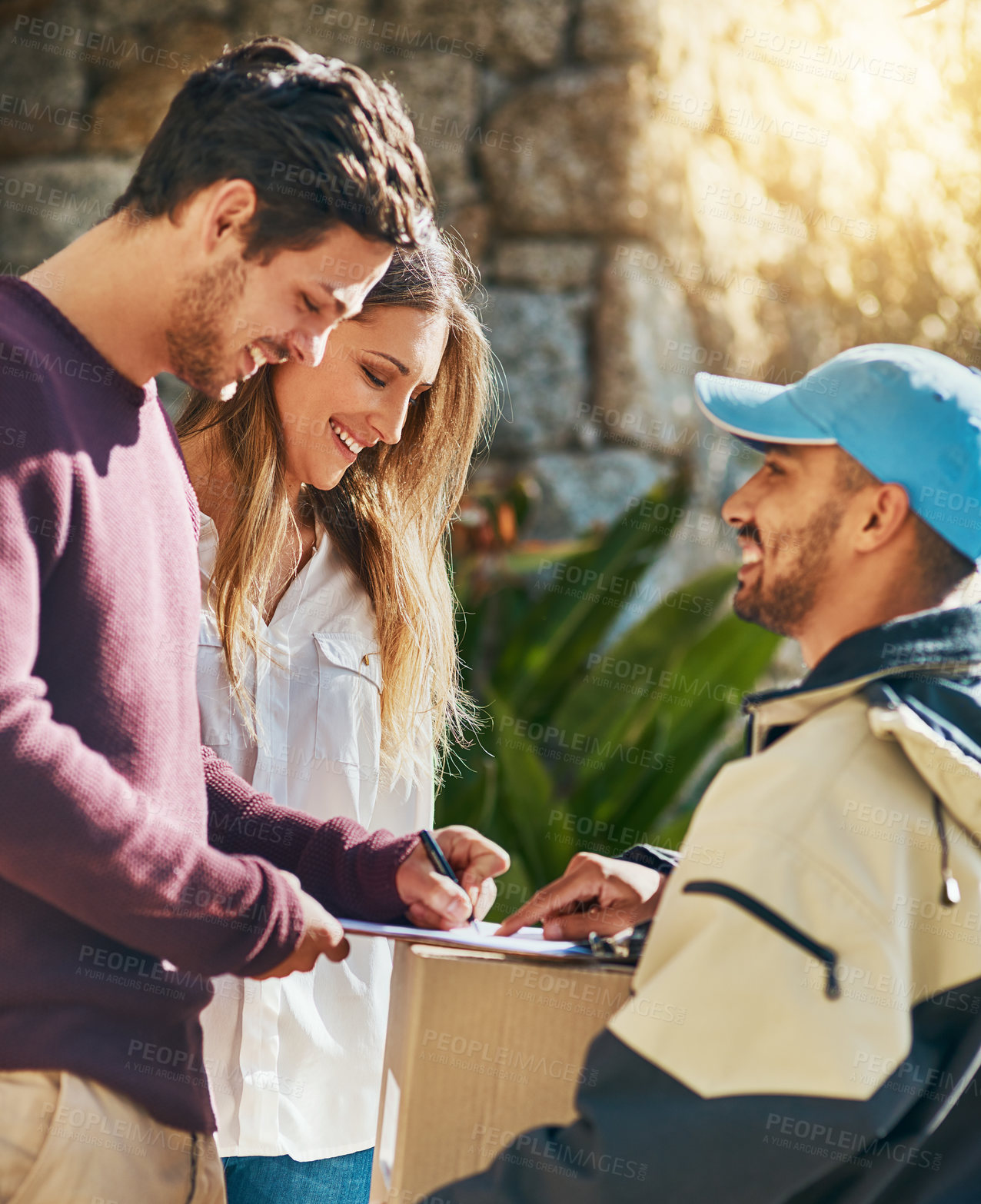 Buy stock photo Shot of a courier making a delivery to a young couple