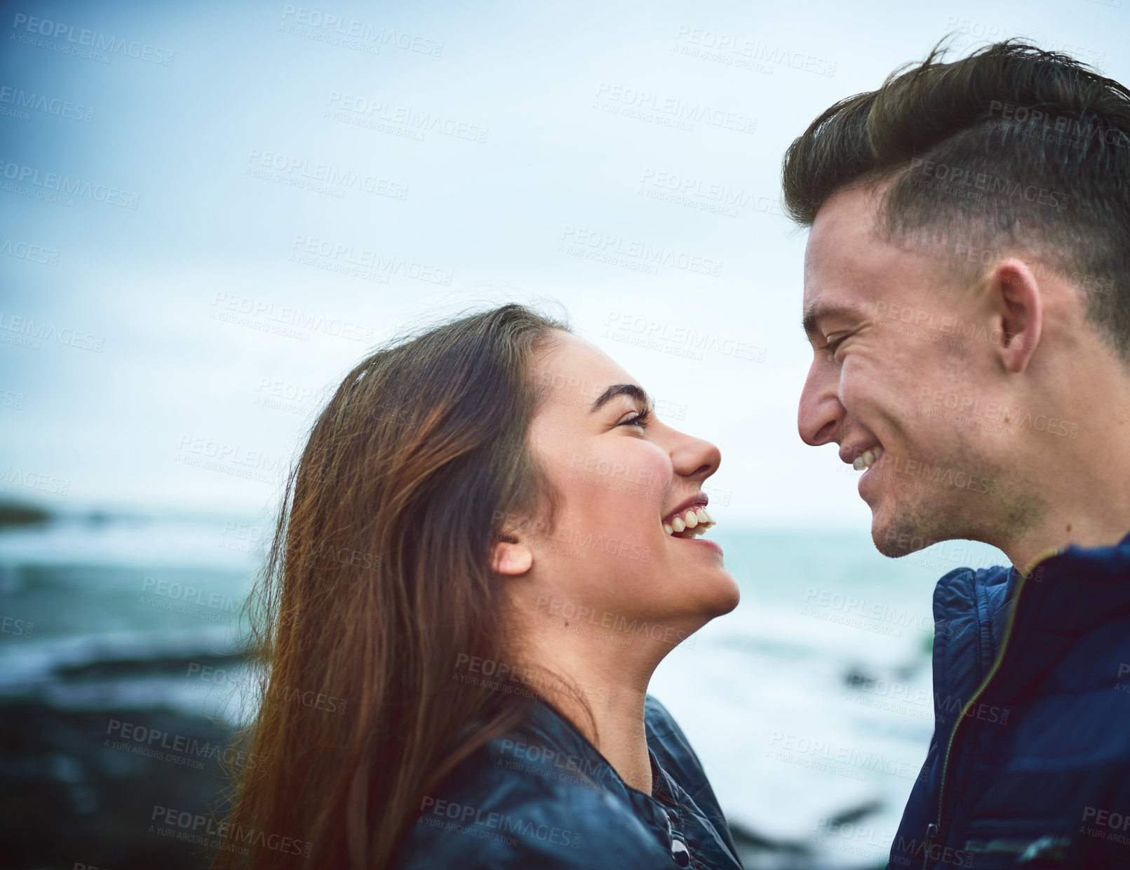 Buy stock photo Outdoor, couple and happy with love at beach for commitment, bonding and romance on anniversary. Man, woman and smile with care by ocean for holiday adventure, vacation and break together in winter