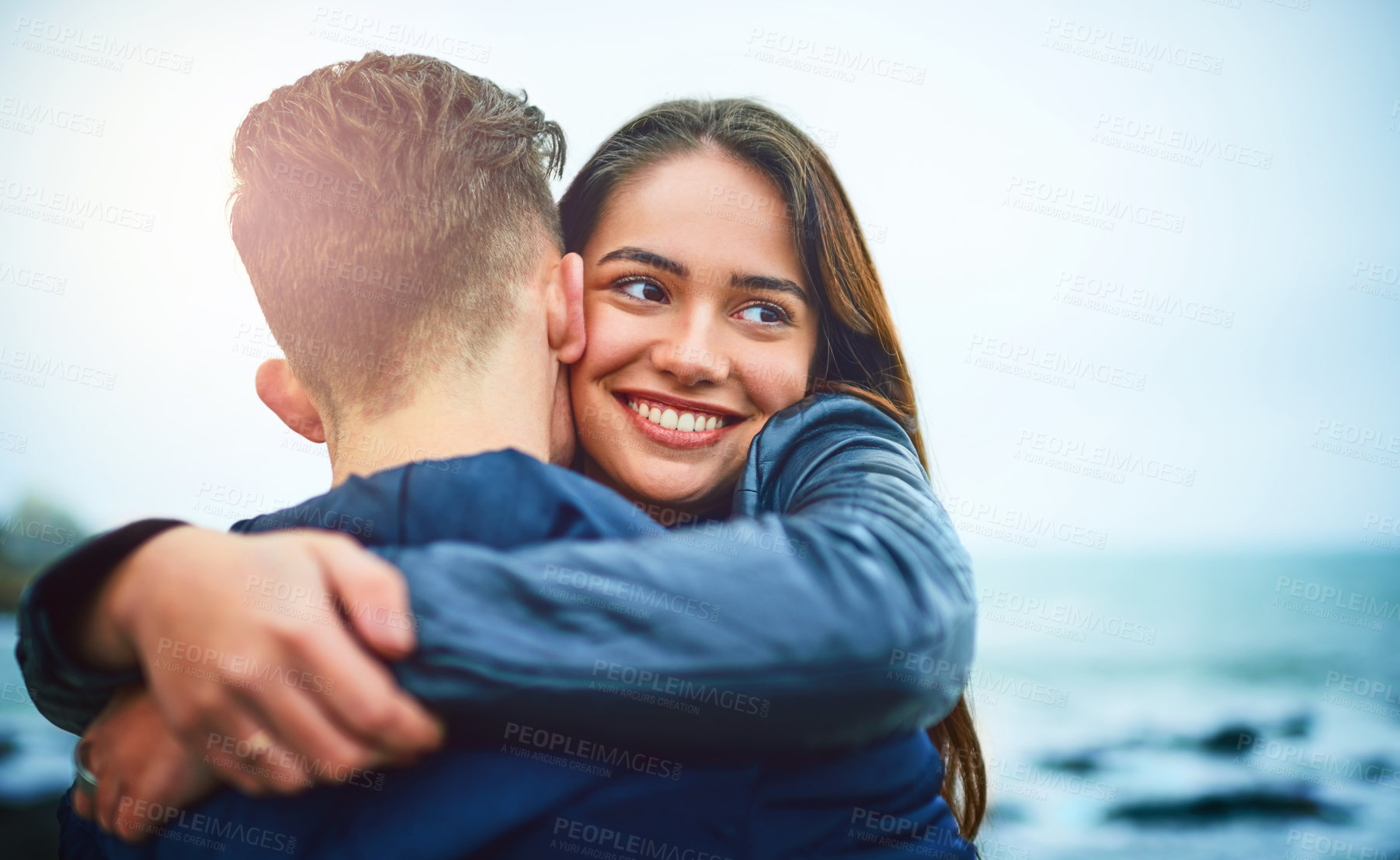 Buy stock photo Girl, hug and couple and outdoor on date by sea with smile, love and ocean with bonding by water. Happy, romance and gen z people together with travel and holiday in winter with support and care