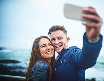 Buy stock photo Shot of a happy young couple taking a selfie outdoors