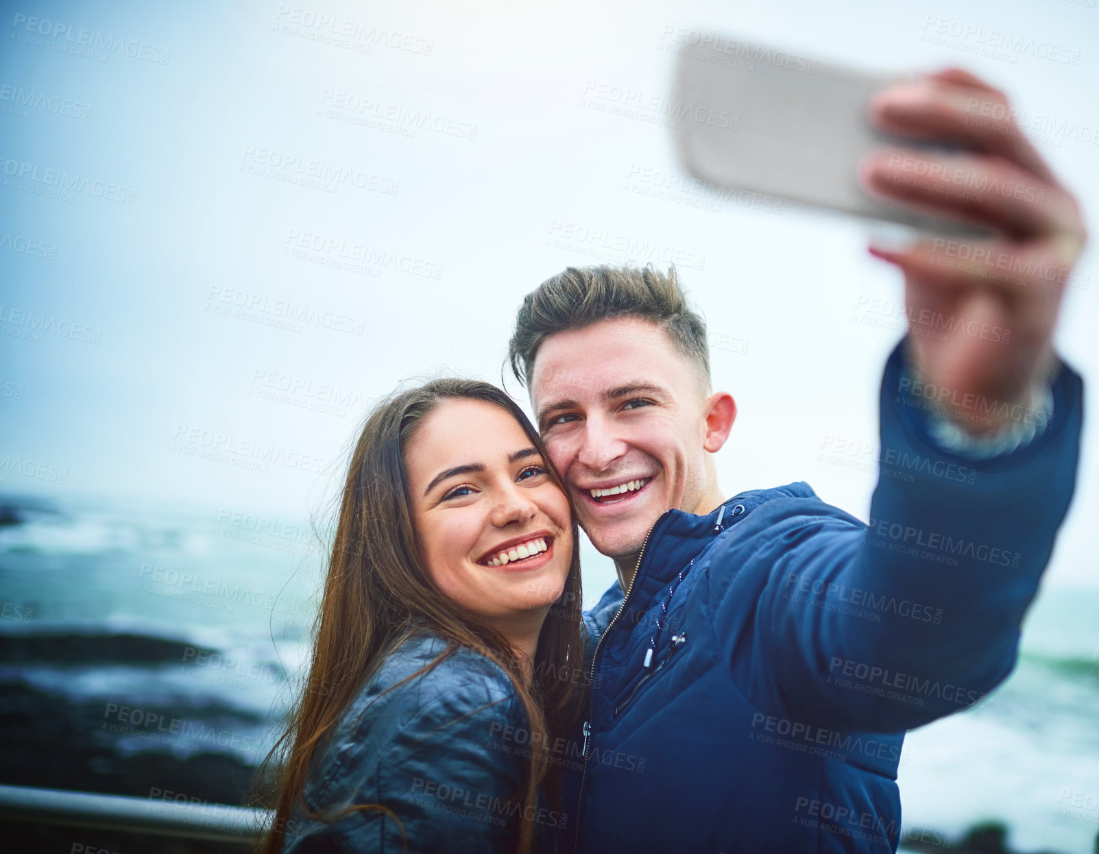 Buy stock photo Shot of a happy young couple taking a selfie outdoors