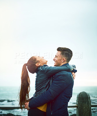 Buy stock photo Couple, hug and sea with smile, love and embrace on date by promenade with mockup. Happy, romance and young people together with travel and holiday in winter with support and care by the ocean