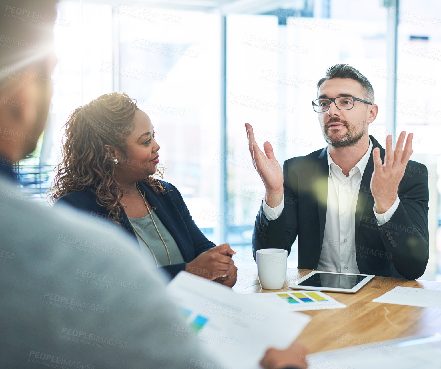 Buy stock photo Cropped shot of a group of corporate colleagues sitting in the boardroom during a meeting