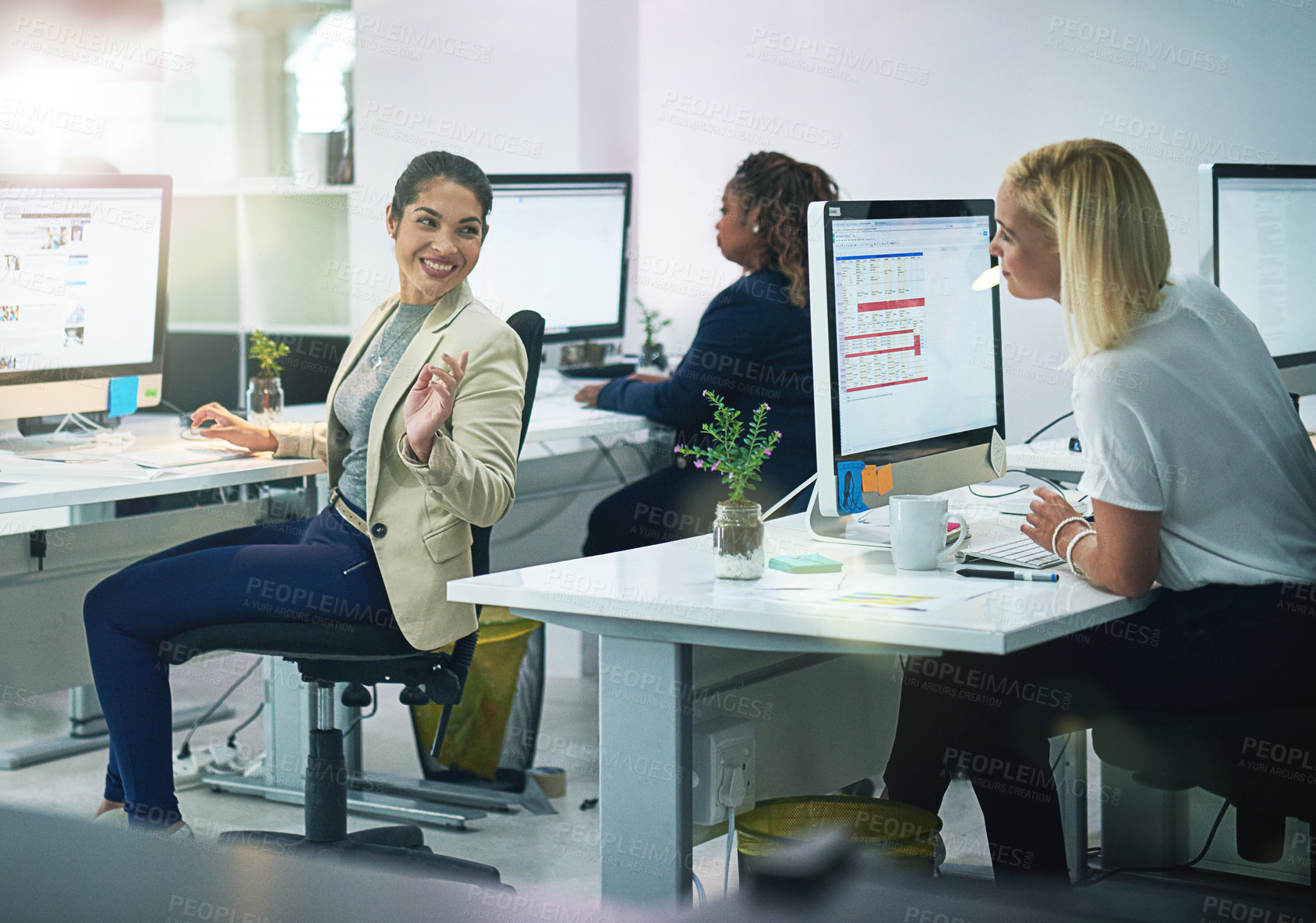 Buy stock photo Shot of two young corporate businesswoman talking while working in their office