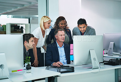 Buy stock photo Cropped shot of a group of corporate colleagues gathered around a computer in their office