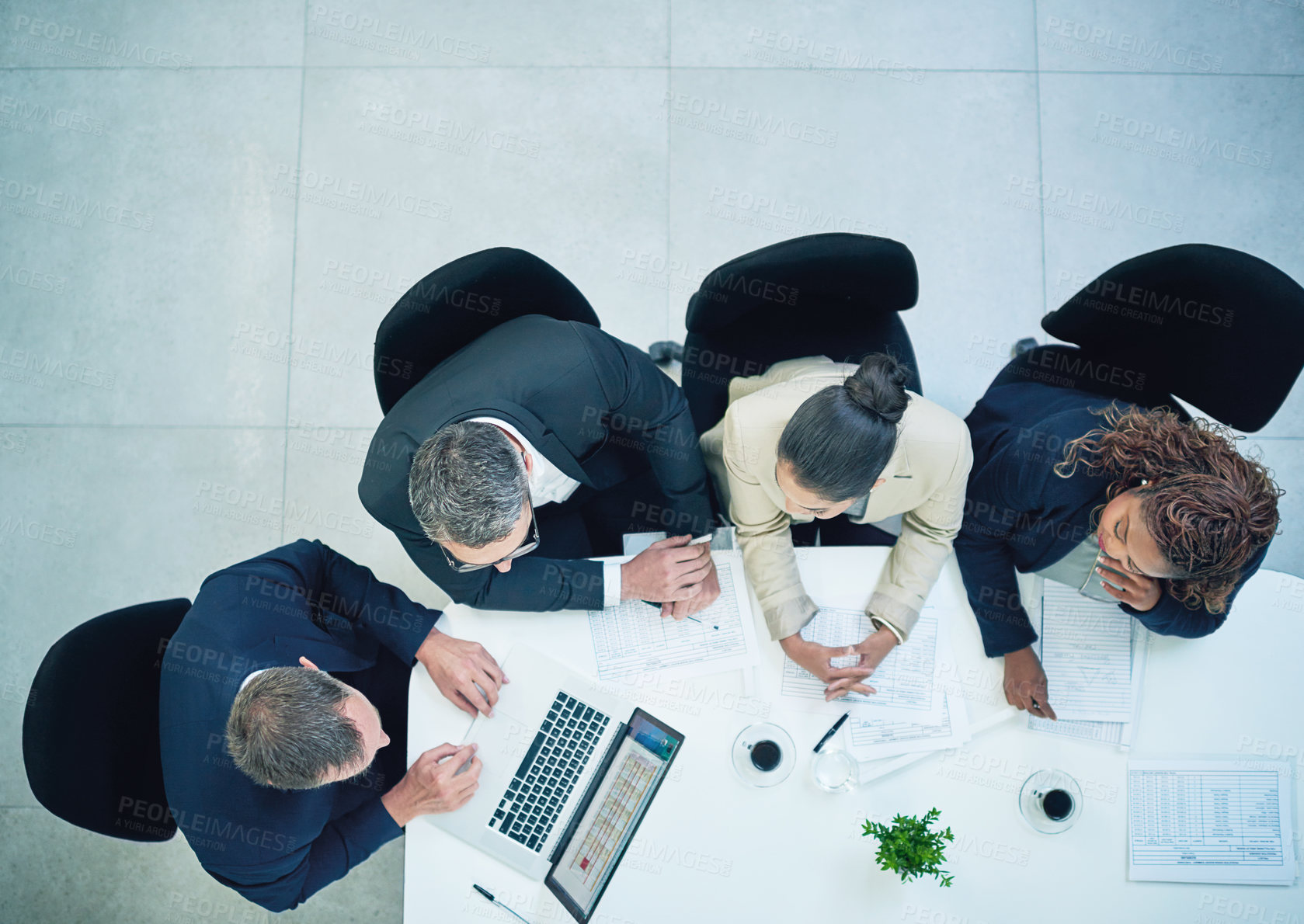 Buy stock photo High angle shot of a group of corporate colleagues sitting in the boardroom during a meeting