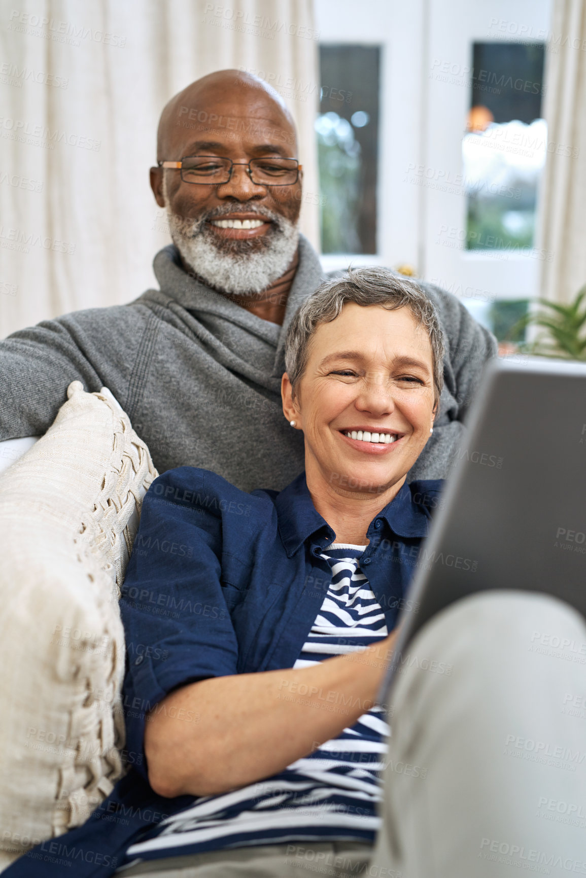 Buy stock photo Tablet, search and happy senior couple on sofa with love, support and sign up service choice while bonding at home together. Interracial, date or old people in living room with app for movie decision