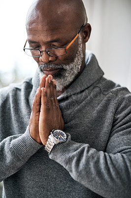 Buy stock photo Cropped shot of a handsome senior man praying while sitting in his home