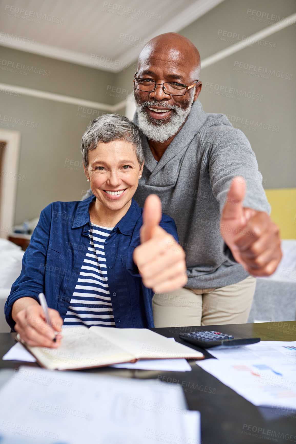 Buy stock photo Cropped portrait of a senior couple giving you the thumbs up while working on their finances at home