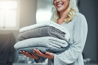Buy stock photo Closeup shot of an unrecognizable woman carrying a pile of towels while doing laundry at home