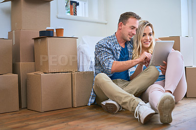 Buy stock photo Shot of a young couple using a digital tablet while moving house