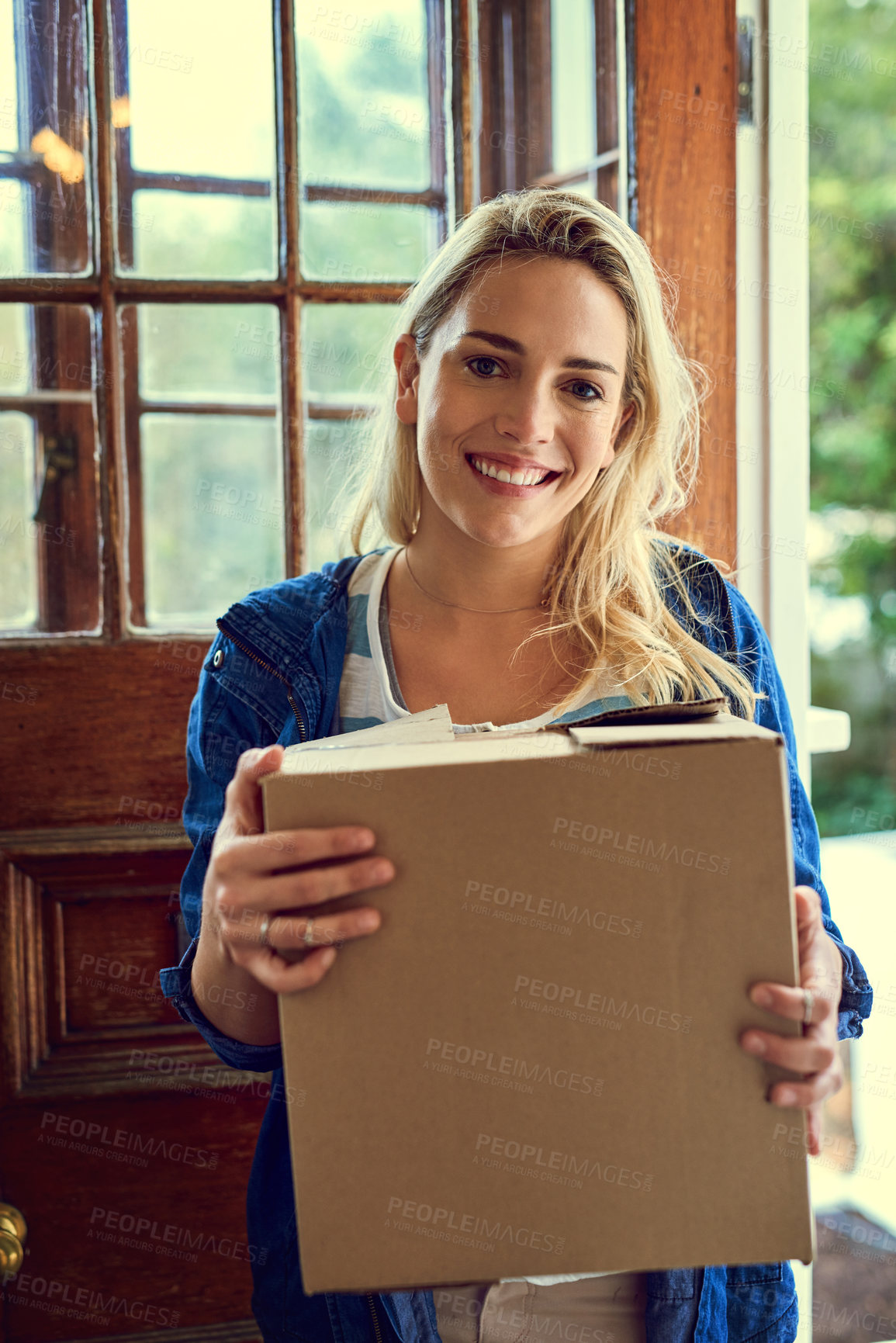 Buy stock photo Portrait of a young woman holding a box while moving house