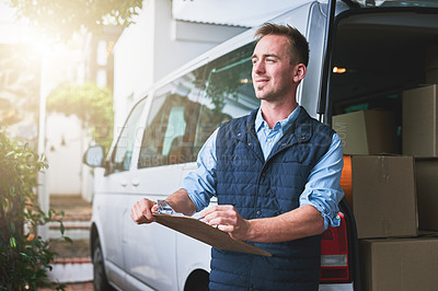 Buy stock photo Shot of a courier checking his deliveries in his van