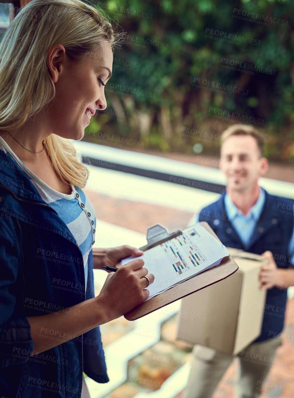 Buy stock photo Shot of a young woman signing for her delivery from the courier