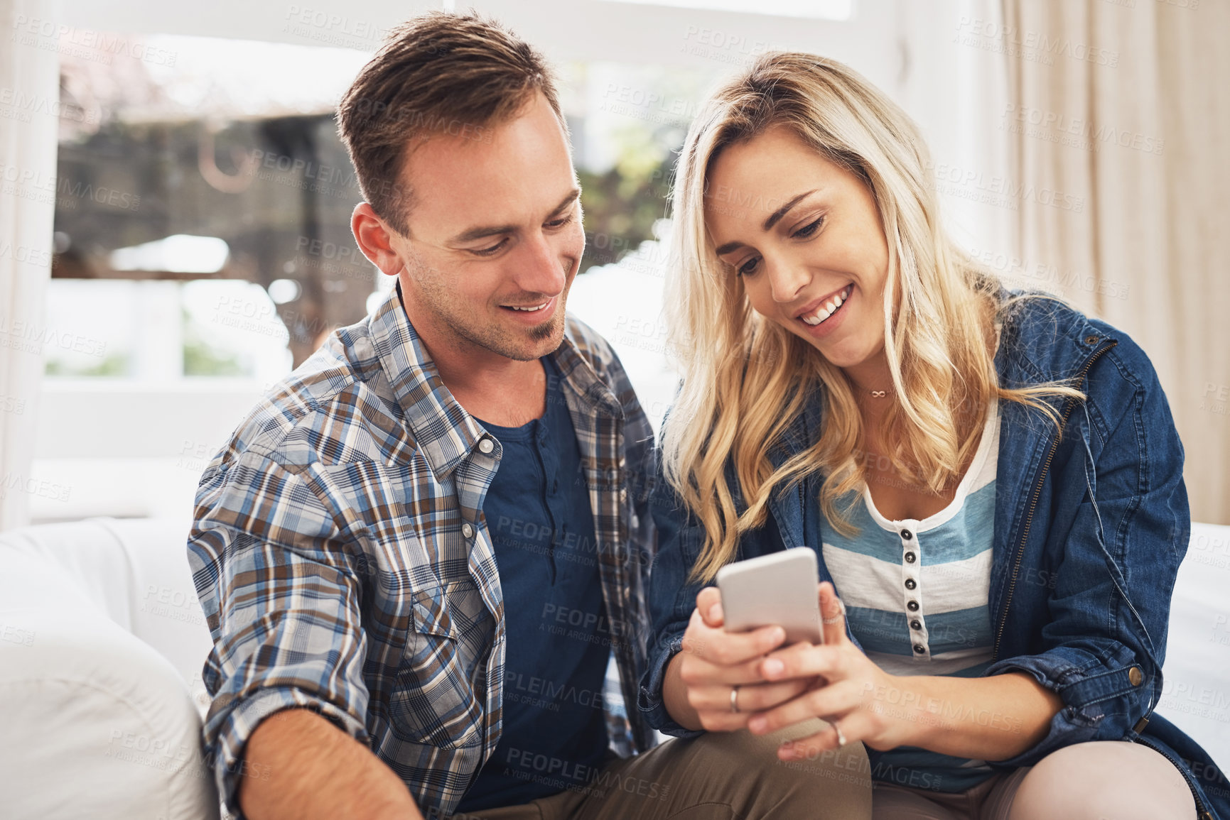 Buy stock photo App, conversation and phone with couple on sofa in home living room together for travel booking. Ecommerce, internet bank or online shopping with man and woman in apartment for accommodation search