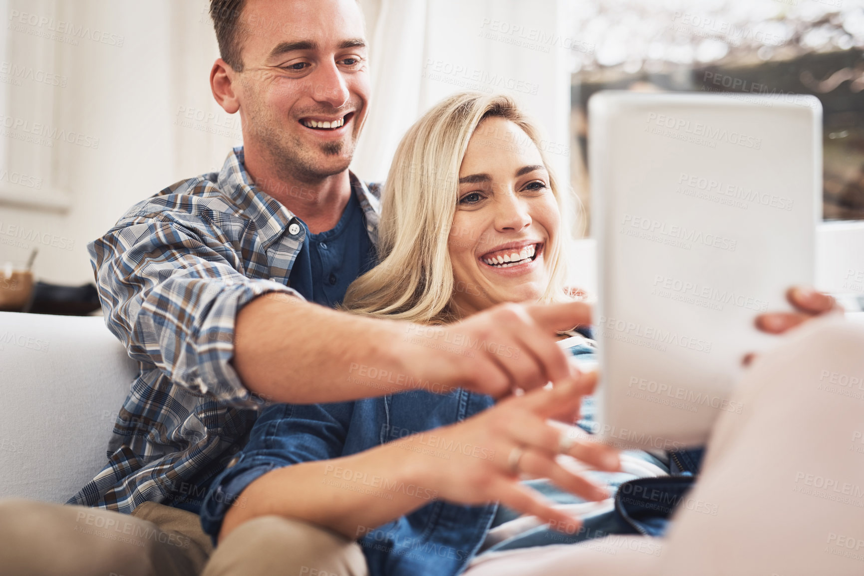 Buy stock photo Shot of a young couple using a digital tablet at home